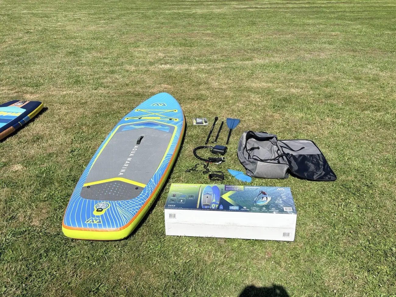 Costco Aqua Marina Revolution inflatable paddle board in Canada with paddle, electric pump, backpack and accessories laid out on grass